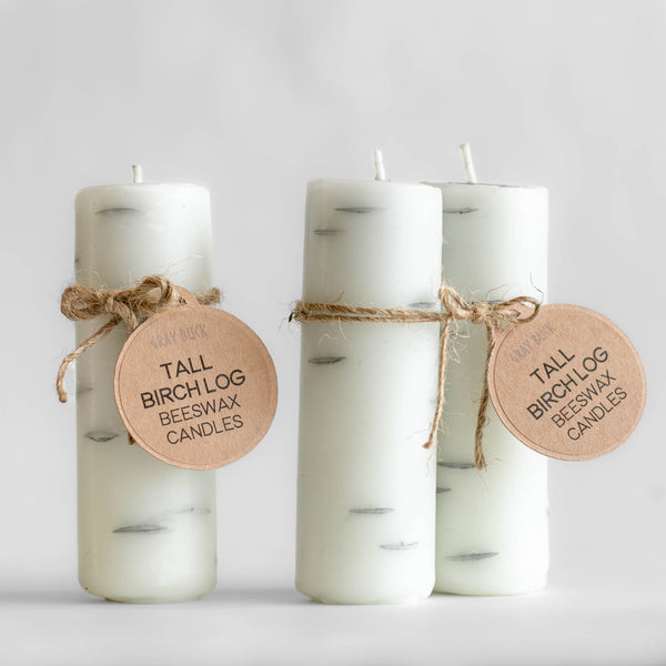 Photo of single and pair of tall Birch Log candles made of 100% Canadian beeswax with Gray Buck tags, standing upright in front of a white background.