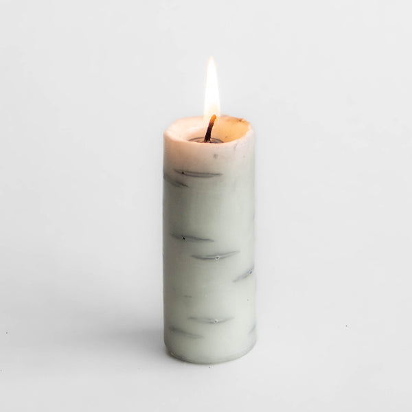 Photo of single tall Birch Log candle made of 100% Canadian beeswax, burning to show interior rings, with white background.